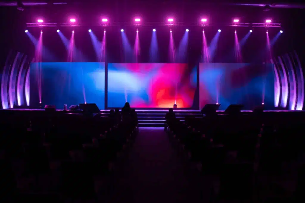 Palco di una conferenza illuminato con luci scenografiche, macchina del fumo e 3 grandi ledwall (Allestimenti scenografici)